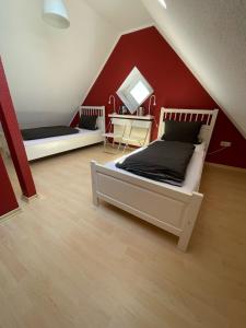 a bedroom with two beds and a red wall at Ferienwohnung KÖÖK I - echter Inselblick in Neuharlingersiel