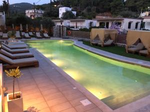 a swimming pool with chaise lounge chairs and a resort at Helen Hotel in Poros