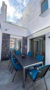 a wooden table and blue chairs on a patio at Super cool villa in Los Cristianos in Los Cristianos