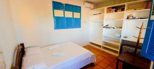 Cette petite chambre comprend un lit blanc et des fenêtres bleues. dans l'établissement Casa com piscina na Praia de Cotovelo by Qavi, à Parnamirim