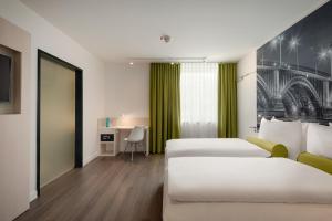 a hotel room with two beds and a desk at Super 8 by Wyndham Koblenz in Koblenz
