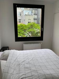 a bedroom with a white bed and a window at Suite minimalist 50m2 in Brussels