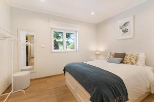 1 dormitorio blanco con 1 cama grande y 2 ventanas en Quinta Vitae en Gradil