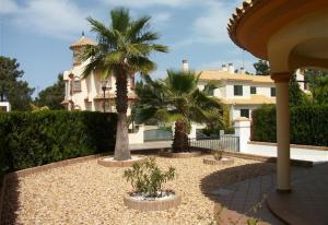 a house with two palm trees in a courtyard at Luxury villa in Islantilla