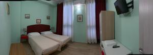ein kleines Zimmer mit zwei Betten und einem Fernseher in der Unterkunft CerrutiHotel in Vercelli