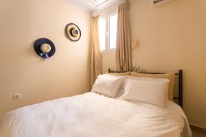 a bedroom with a bed with white sheets and a window at Flash House in Spetses