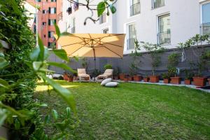 un patio con ombrellone, sedie e prato di GIARDINO IN CENTRO STORICO - Appartamento con giardino, Genova Centro Storico, Acquario a Genova