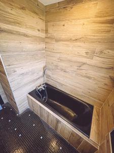 eine Badewanne in einem Zimmer mit einer Holzwand in der Unterkunft Kombi By Carl-Emilie in Épinal