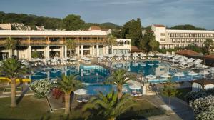 un resort con ampia piscina con ombrelloni bianchi di Roda Beach Resort & Spa a Karousádes