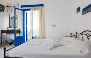a bed with white sheets and a blue door at Vigles in Adamantas