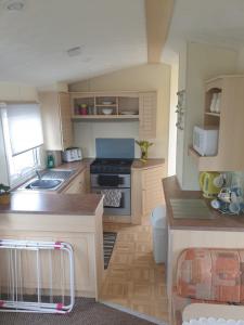 a small kitchen with a sink and a stove at 4 BERTH CARAVAN SILVER BEACH INGOLDMELLS number 90 in Skegness
