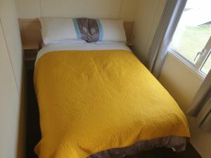 a yellow bed in a small room with a window at 4 BERTH CARAVAN SILVER BEACH INGOLDMELLS number 90 in Skegness