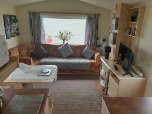 a living room with a couch and a tv at 4 BERTH CARAVAN SILVER BEACH INGOLDMELLS number 90 in Skegness
