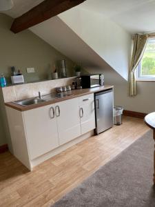 a kitchen with white cabinets and a sink at Arkleside Country Guest House in Reeth