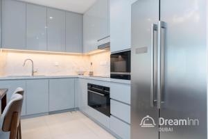 cocina con armarios blancos y nevera de acero inoxidable en Dream Inn Apartments - Address Beach Residence Fujairah, en Fujairah