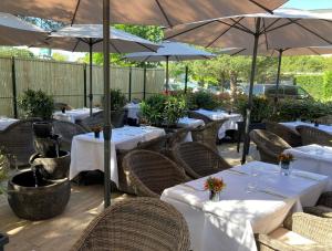 un restaurant avec des tables blanches et des parasols dans l'établissement Le M & Spa by Hôtels & Préférence, à Mérignac