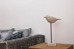 **Authentic & Spacious 5 Bed Apartment/Hyde Park** في لندن: تمثال لطائر على طاولة بجانب أريكة
