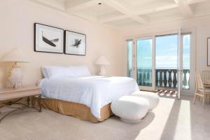 a white bedroom with a large bed and a balcony at Breakers Way Dream in Carpinteria