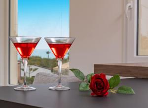 dos copas de vino tinto en una mesa con una rosa en Villa TinaDea, en Pozzallo