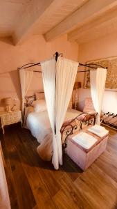 Schlafzimmer mit einem Bett mit Vorhängen und Holzboden in der Unterkunft Agriturismo Fonte Rosa in Fiastra