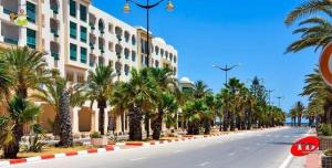 una calle frente a un edificio con palmeras en Résidence aladin en Hammamet Sud