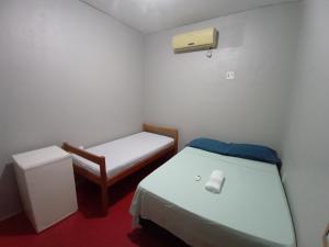 Habitación pequeña con 2 camas y silla en Discovery hostel en Manaus