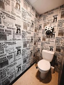 a bathroom with a toilet and a wall covered in newspapers at Kombi By Carl-Emilie in Épinal