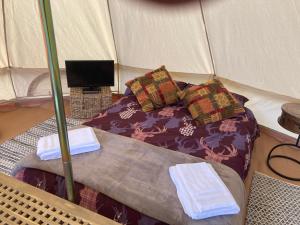 a bed in a tent with two towels on it at Roslin Glamping in Roslin