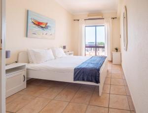 a bedroom with a white bed and a window at Apartamentos Mar-Bel Sol in Vilamoura