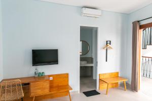 a living room with a tv on a white wall at Coco & Pineapple Pants Hostel - CANGGU, BALI in Canggu
