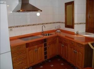 a kitchen with wooden cabinets and a sink and a mirror at Casa Rural Frutos in San Esteban de la Sierra