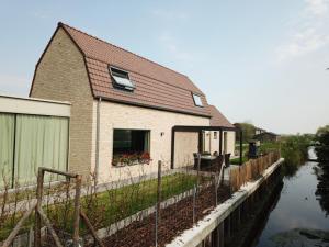 a house with a fence next to a river at De Groene Bever in Lo-Reninge