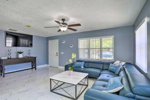 a living room with a blue couch and a ceiling fan at Modern Clearwater Home with Deck 9 Mi to Beach in Clearwater
