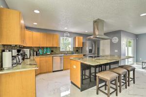 a large kitchen with wooden cabinets and bar stools at Modern Clearwater Home with Deck 9 Mi to Beach in Clearwater