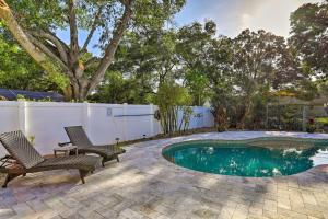 a backyard with a pool and two chairs and a fence at Modern Clearwater Home with Deck 9 Mi to Beach in Clearwater