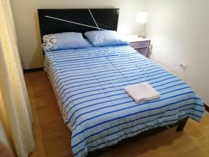 a bedroom with a bed with a blue and white striped comforter at YLLARICH in Trujillo