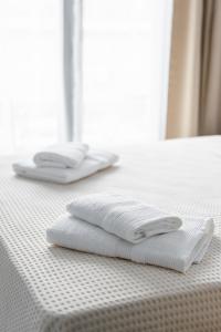 two white towels sitting on top of a bed at Boho Rooms in Thessaloniki