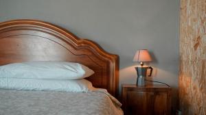 a bed with a wooden headboard and a lamp on a table at B&B La Buonora in Sinio