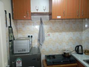 a kitchen with a microwave and a stove with two wine glasses at The Red Nest Nahashon Kimemia One Bedroom in Nairobi