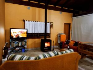 a living room with a couch and a tv at Bosque Urbano - Cobertura Privativa com Lareira e Piscina in Bom Princípio