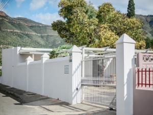 a white fence with a gate and mountains in the background at River Bend Cottages in Graaff-Reinet