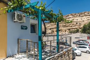 a building with a blue trellis next to a parking lot at Malamatenia in Matala