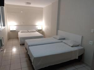 a hotel room with two beds and two lamps at Habitat Hotel de Leme Ltda in Leme