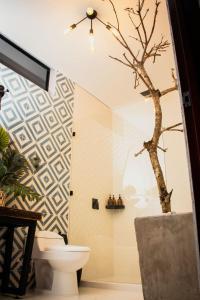 a bathroom with a toilet and a tree on the wall at Santuario Luxury Eco Hotel in Villeta