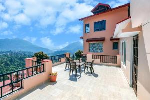 a balcony of a house with tables and chairs at Ceedar Cottages in Bhīm Tāl