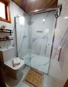 a bathroom with a glass shower and a toilet at Chalé Bosque das Pedras in Núcleo Mauá +12 photos