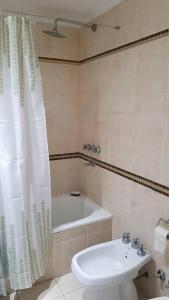ein Badezimmer mit einem WC, einem Waschbecken und einem Duschvorhang in der Unterkunft Gurruchaga Suites free parking Movistar Outlet in Buenos Aires