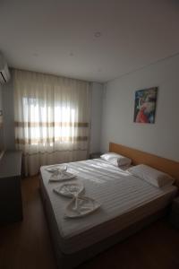 Schlafzimmer mit einem Bett mit weißer Bettwäsche und einem Fenster in der Unterkunft Mane Apartments in Sarandë