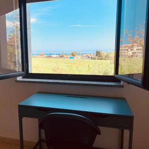 einen Schreibtisch mit einem Fenster mit Blick auf ein Feld in der Unterkunft Il soggiorno diVino in Cirò Marina