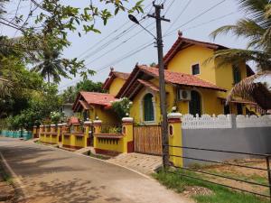 a yellow house with a white fence in front of it at Villa Agastya in Betalbatim